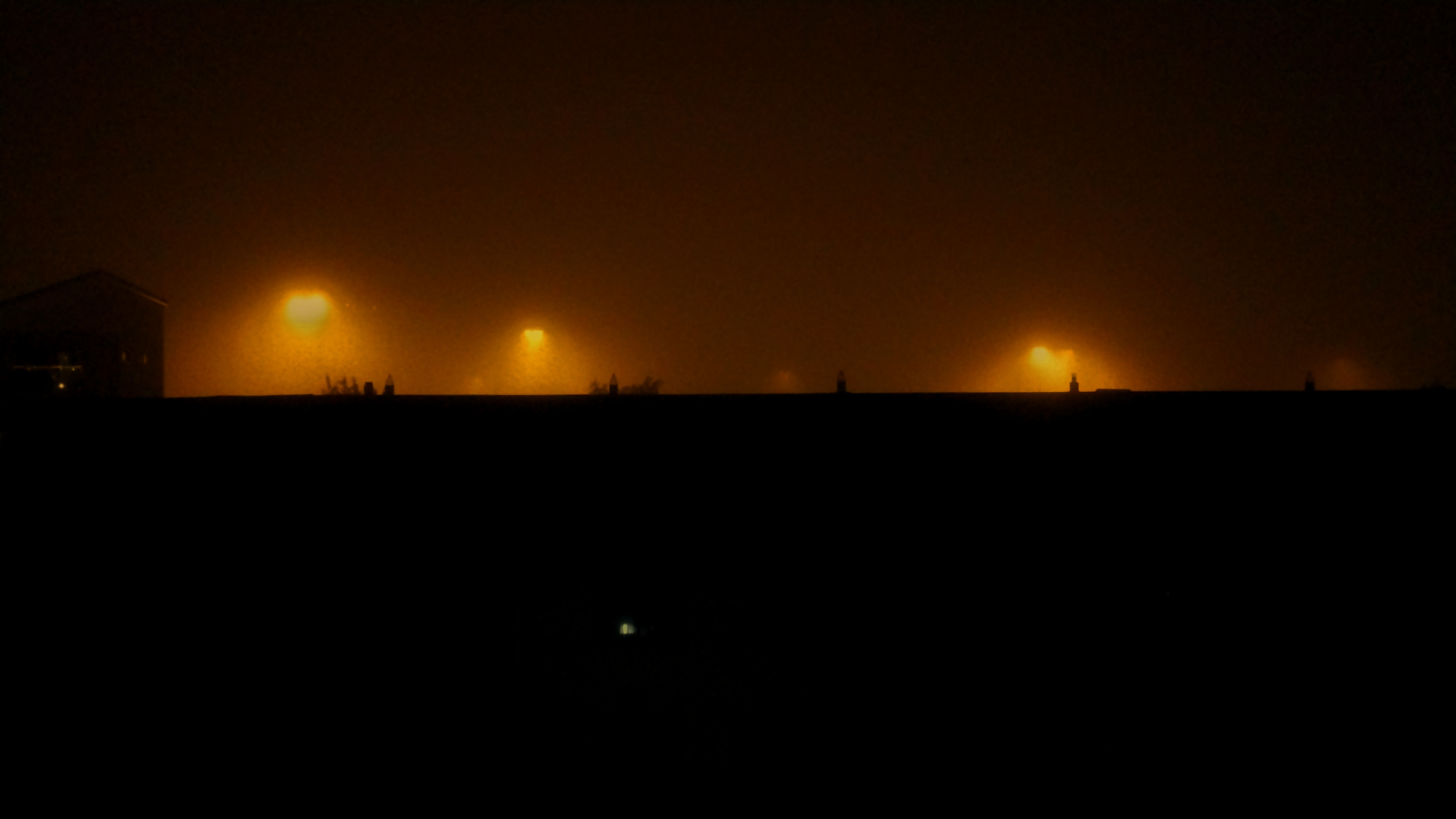 A eerie rainy night scene with orange lights.
